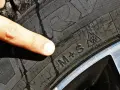 Dito indice indica il simbolo del fiocco di neve su un battistrada gomme invernali M+S, pronto per la neve.