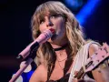 Taylor Swift śpiewa do różowego mikrofonu, grając na gitarze. To scena z jej epickiej trasy "reputation stadium tour", która na zawsze zmieniła jej wizerunek.