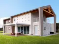Casa moderna con tetto in legno a vista, facciata decorata con quadrati colorati e un portico bianco.