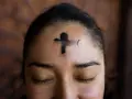 A cross of ashes marks a forehead, a solemn reminder of scripture for Ash Wednesday.