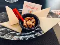 Queso en cuñas con nueces en un cuenco negro, sobre plato de cristal y tarjeta "Reino de Navarra".