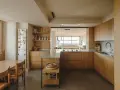 Cocinas color madera con encimeras de granito, electrodomésticos integrados y una isla central. Un comedor adyacente con mesa y sillas de madera.