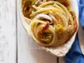 Un piatto di pasta con fiori di zucca cremosa, condita con acciughe e servita in una ciotola decorata.