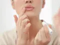 Una mujer aplica bálsamo labial, mostrando cómo son los labios perfectos: hidratados y suaves.