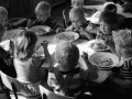Kinder essen gemeinsam Brei. Ein Junge isst genüsslich, ein anderes Kind schaut nachdenklich. Erinnerungen an Kindheits Eis.