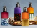Vier bunte Parfumflaschen mit silbernen Verschlüssen auf goldenem Untergrund.