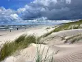 Piaszczyste wydmy porośnięte trawą morska, z widokiem na wzburzone morze i niebo z chmurami. Idealne kąpielisko na mierzei wiślanej.