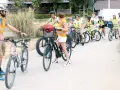 Un groupe d'enfants à vélo, encadrés par des adultes en gilets de sécurité, suit un parcours. La scène illustre la réglementation du déplacement à pied et à vélo à l'ACM.