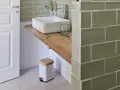 Plan de travail pour salle de bain avec lavabo carré, robinetterie moderne et poubelle design.