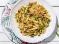 Un piatto invitante di pasta fredda con zucchine e salmone, condita con basilico fresco. Perfetta per un pasto estivo leggero e gustoso.