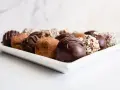 Variedad de trufas de chocolate, algunas cubiertas de cacao y otras con frutos secos picados. ¡Perfectas para aprender como hacer trufas de chocolate!