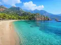 Piękna plaża w Turcji z turkusową wodą, górami i sosnami. Idealne miejsce na relaks.