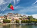 Wspaniała portugalia pogoda w grudniu. Flaga Portugalii powiewa nad malowniczym miastem na wzgórzu, z rzeką w tle.