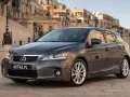 Szary Lexus CT 200h zaparkowany na brukowanej uliczce z zabytkowymi budynkami w tle.