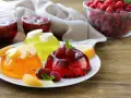 Tre colorate gelatine per dolci, guarnite con frutta fresca, invitano a un assaggio rinfrescante.