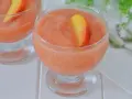 Coppa di granita alla pesca, rinfrescante e dolce, guarnita con una fetta di pesca fresca. Perfetta per un'estate golosa.