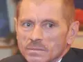 Portret Stanisława Pąka. Mężczyzna z wąsikiem patrzy w bok. W tle owoce.