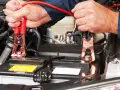 Mani che collegano i cavi per avviare moto con batteria auto.