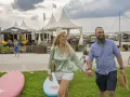 Glückliches Paar spaziert am **Stein Ostsee Strand** entlang, vorbei an SUP-Boards und Strandbuden.
