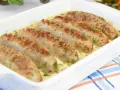 Aromaticzna biała kiełbasa w sosie chrzanowo-musztardowym, udekorowana świeżym koperkiem, podana w białej zapiekance.