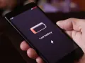 Dłoń trzyma smartfon z komunikatem "Low battery". Czas na naukę, jak oszczędzać baterię w telefonie, by uniknąć takich sytuacji.