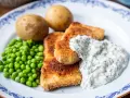 Panerad fisk med kokt potatis, gröna ärtor och en krämig skolans dillsås.