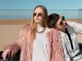 Chica con abrigo rosa peludo y collar dorado, apoyada en un chico con camisa blanca. Inspiración para como ser una chica aesthetic.