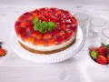 Eine köstliche Erdbeer Joghurt Sahne Torte, bedeckt mit frischen Erdbeeren und Tortenguss, garniert mit Minze.