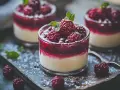 Tre läckra panna cotta i glas, toppade med hallon och mynta. Pudrade med florsocker.