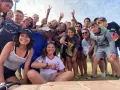 Un groupe d'enfants souriants fait un selfie en plein air, certains faisant le signe de paix.