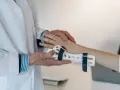 Lekarz zakłada pacjentowi ortezę na nadgarstek, co jest częścią terapii przy cieśni nadgarstka. Ćwiczenia pomogą w rehabilitacji.