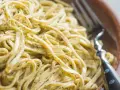 Un primo piatto invitante di tagliolini al limone, conditi con una salsa cremosa e profumata, pronti per essere gustati con una forchetta.