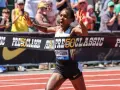 Faith Kipyegon przekracza linię mety z uniesionymi rękami, triumfując na bieżni.