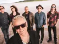 Zespół Wilki skład na plaży, w tle morze. Muzycy w okularach przeciwsłonecznych, każdy w innym stylu.