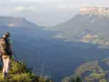 Randonneuse contemplant un panorama grandiose lors d'une traversée de la Chartreuse. Les montagnes s'étendent à perte de vue.