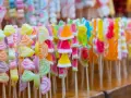 Coloridas manualidades con chuches en palitos, formando un arcoíris de dulces.