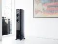 Elegancki głośnik Dynaudio Contour 30 w nowoczesnym wnętrzu, obok okna z widokiem na miasto.