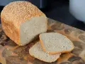 Frisch gebackenes sesam brot, mit zwei Scheiben auf einem Holzbrett.