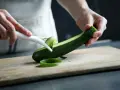 Manos pelando un calabacín para preparar deliciosas recetas con calabacín.