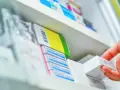 Dłoń sięga po białe pudełko leku, obok widać opakowania z napisem Zinnat.