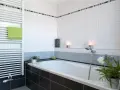 Salle de bain moderne avec baignoire, radiateur blanc et carrelage impeccable. Les joints de carrelage sont parfaits, donnant une finition propre.