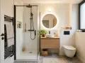 Salle de bain moderne avec douche à l'italienne aux dimensions parfaites, meuble vasque en bois, miroir rond lumineux et WC suspendu.