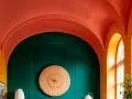 Fotos de paredes y techos pintados en tonos vibrantes: naranja, verde esmeralda y coral. Un reloj de madera decora la pared.