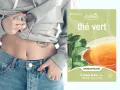 Une personne montre son ventre plat, suggérant la perte de poids, à côté d'une boîte de thé vert antioxydant.