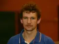 Tomasz Wronka, z kręconymi włosami i wąsami, w niebieskiej koszulce polo.