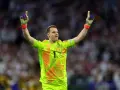 Manuel Neuer, bramkarz w neonowożółtej koszulce z numerem 1, świętuje zwycięstwo, unosząc ręce w geście triumfu.