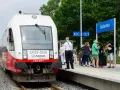 Pociąg Arriva z napisem HEL czeka na pasażerów w Jastarni. Ludzie z bagażami stoją na peronie, gotowi do podróży z Helu do Gdańska.