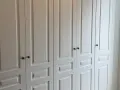 Armario empotrado blanco con puertas de paneles y tiradores oscuros. Perfecto para forrar armario empotrado y dar un toque elegante.