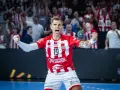 Piłkarz ręczny Ostrovii Wielkopolski w emocjonalnym okrzyku radości po zdobyciu bramki. Tłum kibiców na trybunach.