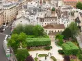Vista aérea de un barrio latino con edificios antiguos, calles estrechas y un parque verde con gente disfrutando del día.